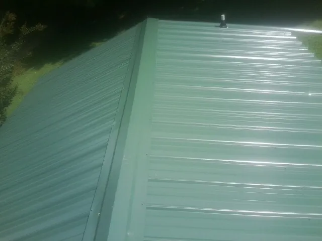 New green metal panels meeting at the ridge of a roof — Flat Roof Repair work by our crew in Bayside