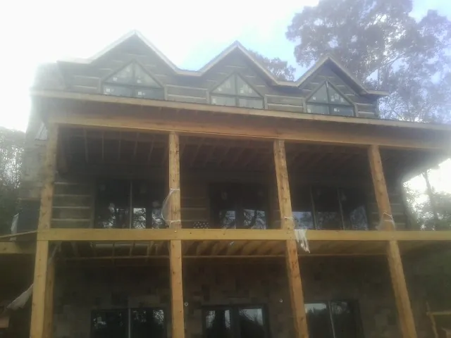 Dormers and porch framing on a large log home under construction — Roof Coating work by our crew in Bayside