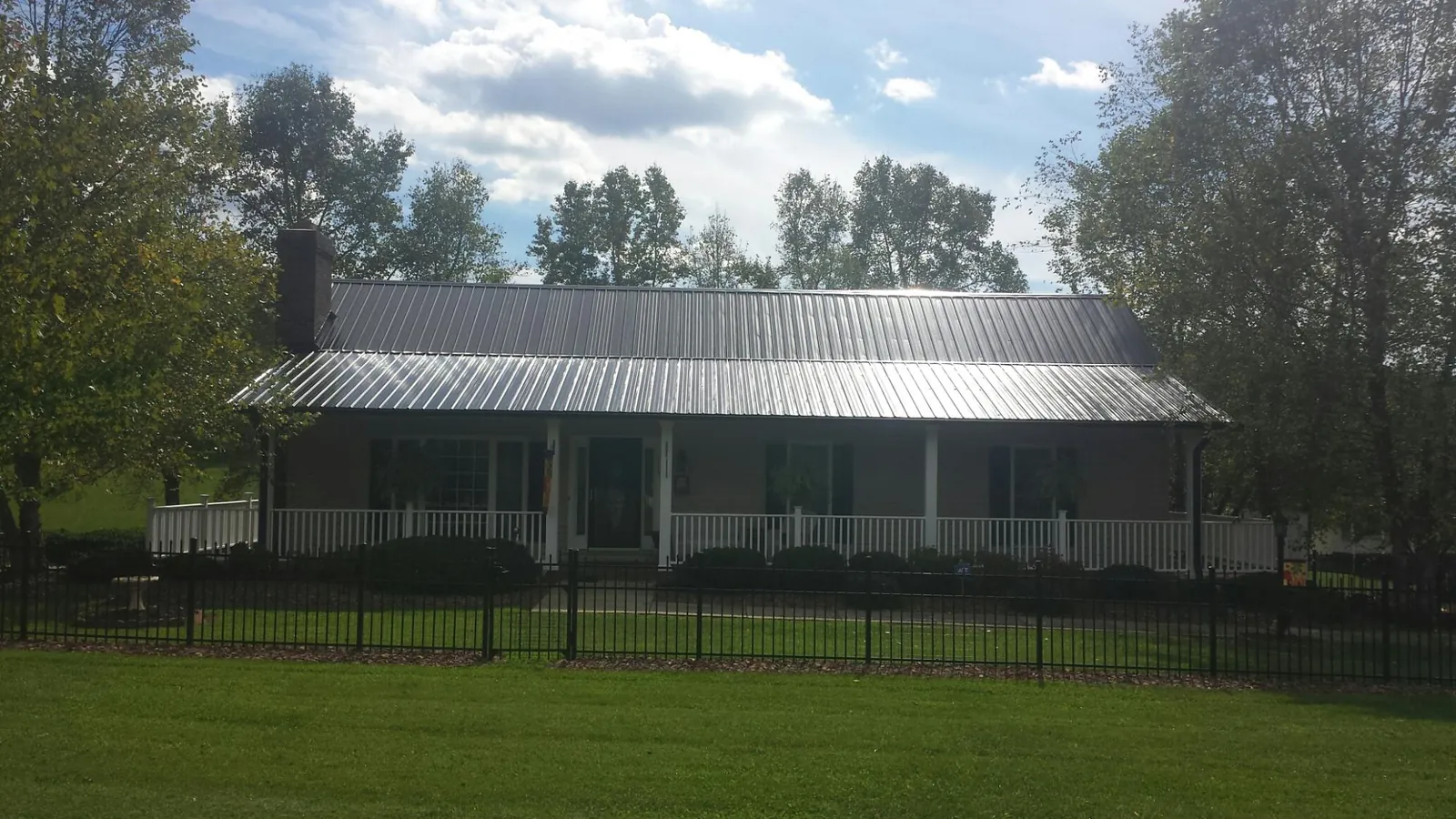 Gray metal roof on a brick ranch with a full width front porch — Gutter Guard Installation work by our crew in Bayside